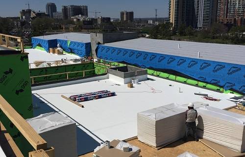 Home 6 Commercial low-slope membrane roof installation with roofing materials staged on the roof.